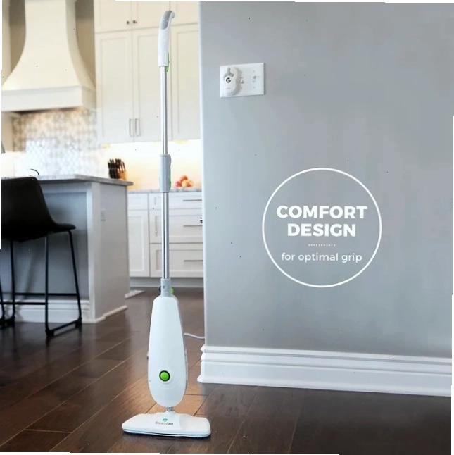 Máy làm sạch hơi nước màu trắng trên sàn gỗ với không gian bếp mờ phía sau, có chữ Comfort Design